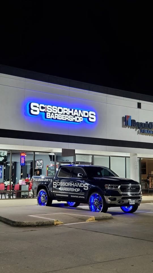 Scissorhands Barbershop storefront at night